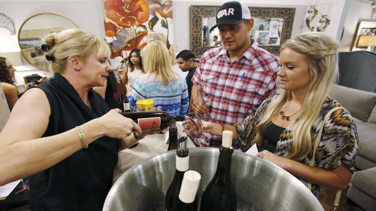 Meegan Huff, left, pours some CASS wine for Drew Domres and Kirsten Ward at the Brick and Mortar furniture store in Old Town Clovis during the Wine Walk on Oct. 3, 2015.