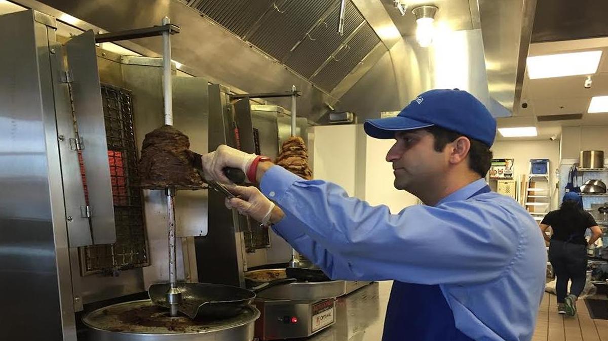 Berlin Street Grill demonstrates how the restaurant’s meat is sliced off of the vertical grill. The meat is served in a sandwich, wrap or salad.