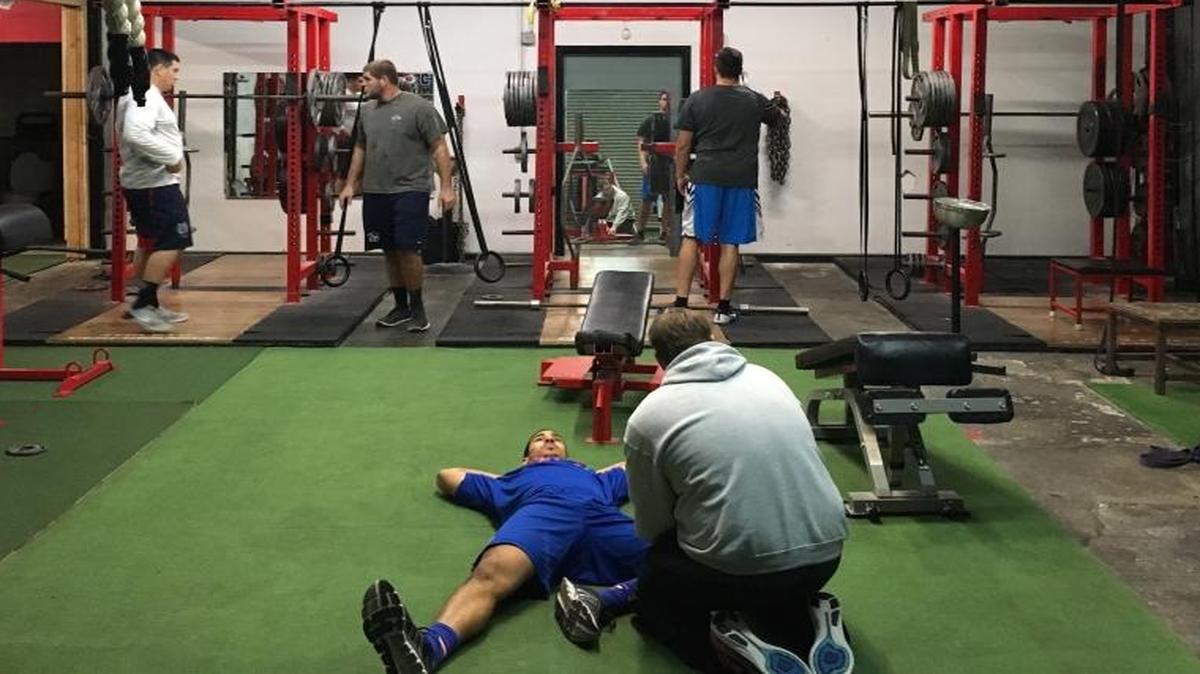Owner and strength and conditioning coach David Standifer (kneeling) works with college football seniors preparing for the NFL draft.