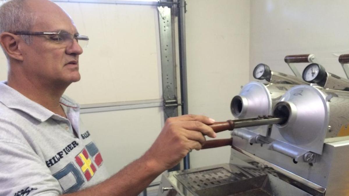 Orlando Costa checks the color of the coffee beans he’s roasting.