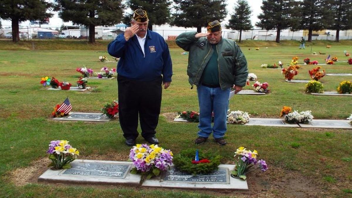 VFW Post Cmdr. August Flash and Bob Brockshire salute while placing wreaths at fallen veterans’ graves in Clovis last December. The VFW is collecting donations to purchase wreaths for this year’s Wreaths Across America program.