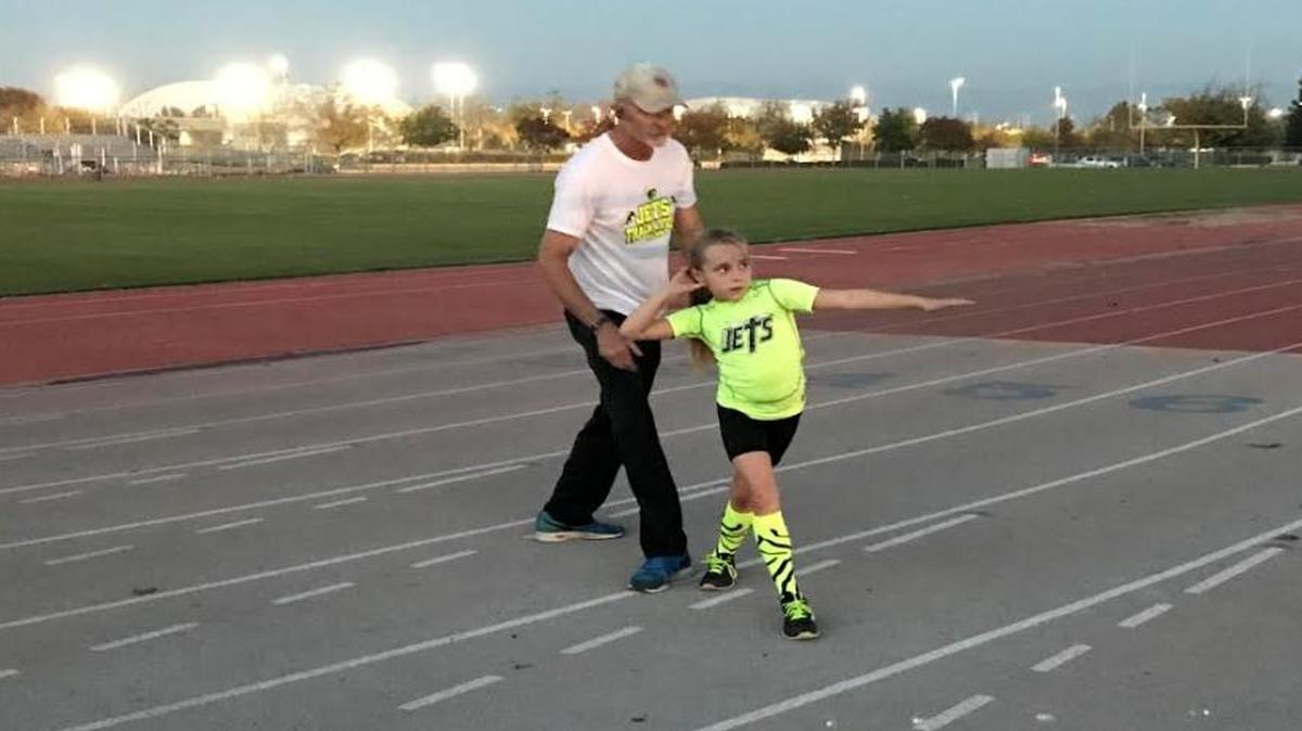 Assistant head coach Robert Fain teaches rotational shot put technique to Lexi Schartmann, a third grader at Reedley’s Immanuel Elementary.