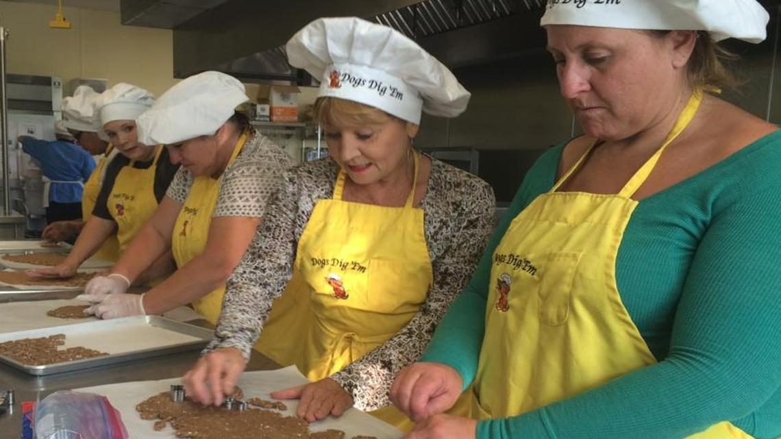 Women cut out Dogs Dig ‘Em treats from all natural dough in the pastry kitchen of Institute of Technology of Clovis.