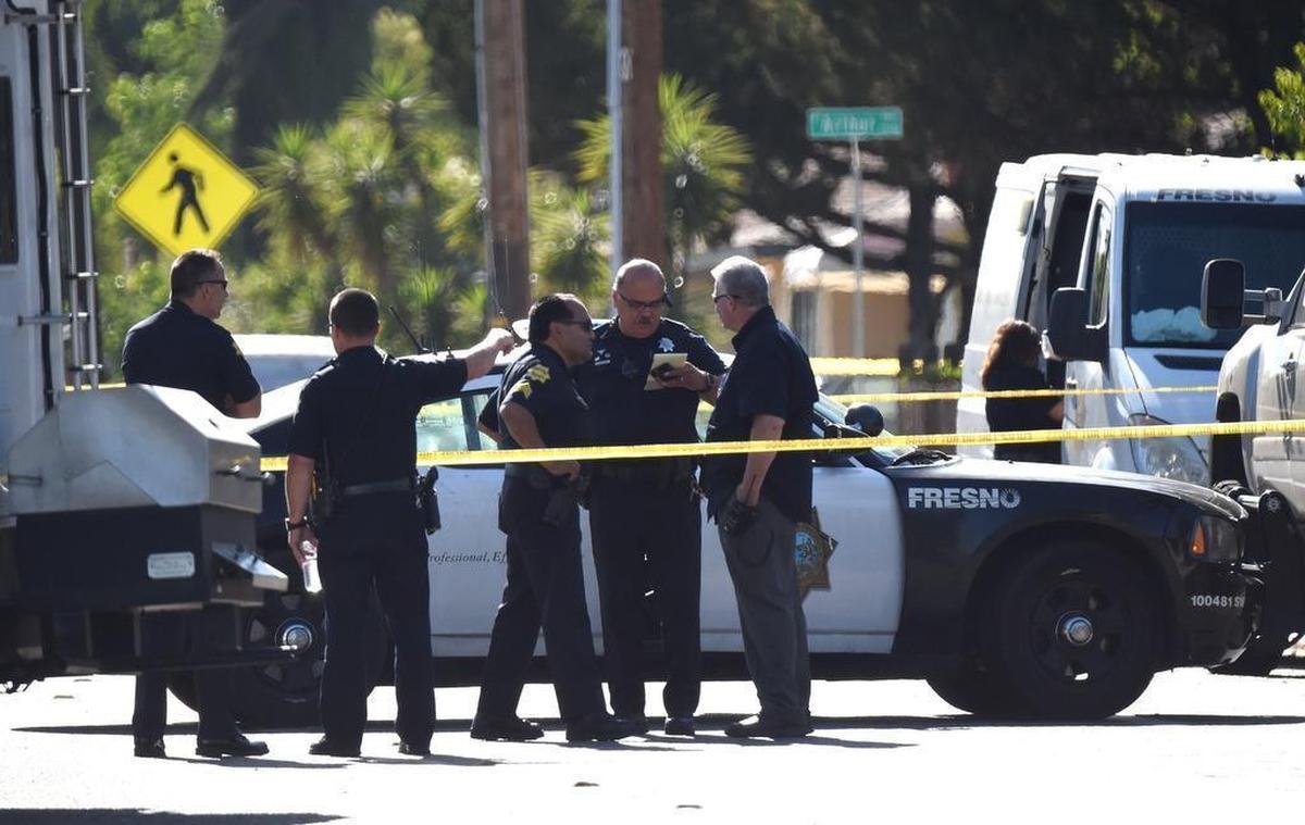 Fresno police officers confer on Dakota Avenue at the scene of an fatal shooting. Police said a suspected gang member fired about 100 rounds, including in the direction of police, before officers was shot and mortally wounded him early Wednesday morning, June 7, 2017.
