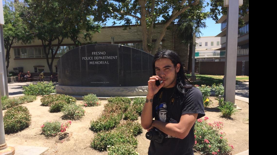 
Brian David Sumner, 26, smokes a cigarette in front of the Fresno Police Department Memorial to officers killed in the line of duty. Sumner goes on trial on Monday, July 13, 2015, facing a charge of misdemeanor vandalism for chalking anti-police slogans on the memorial.
