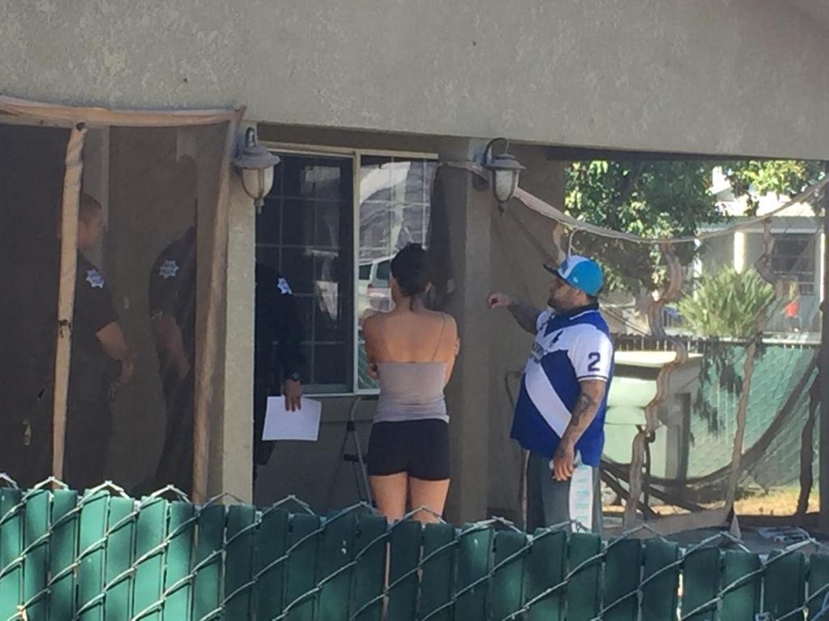 Two people who were inside a vacant home on El Monte Way near Orange Avenue in southeast Fresno on Wednesday wait for police officers.