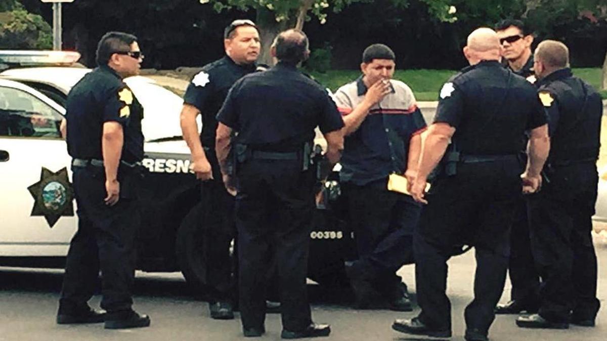 
Arnulfo Martinez (center, with cigarette) confers with Fresno police officers after he stopped a carjacking suspect Friday, July 10.
