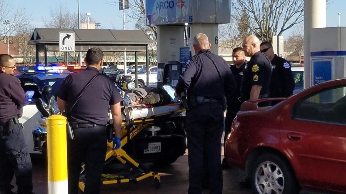 Police surround Francisco Vega, who was arrested and then restrained because he was acting erratically Sunday afternoon in central Fresno.