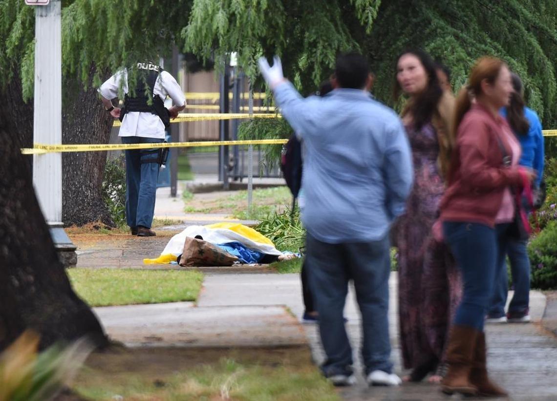 Evacuated office workers, on Fulton Street, north of Nevada, wait for word that they can leave, as police conduct their investigation early on in the triple shooting case, as the covered body of the second victim Mark Gassett, next to his bag of groceries that he had picked up at Catholic Charities, lays where it fell.