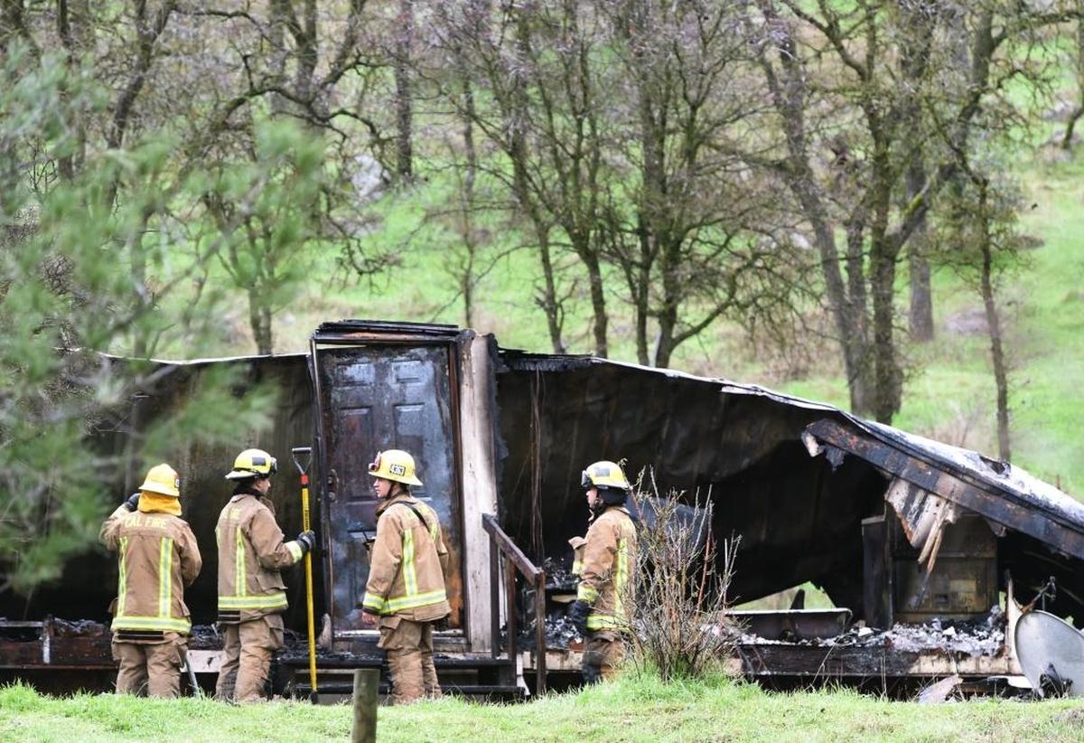 A group of Cal Fire firefighters confer after putting out a mobile home fire- where sex offender Jeffrey Snyder was to be housed- at Dunlap on Sage Lane in January.