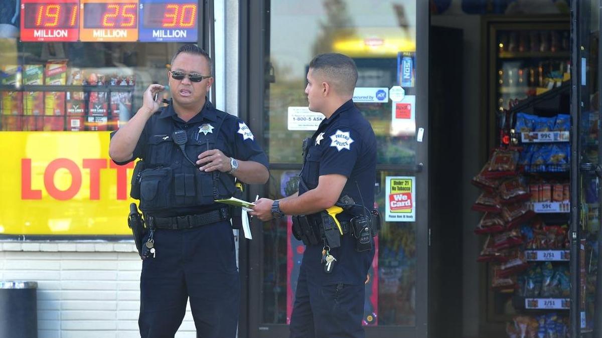 Fresno police officers confer at the site of a shooting at a gas station at Parkway Drive and Ashlan Avenue Wednesday morning, Oct. 25, 2017.
