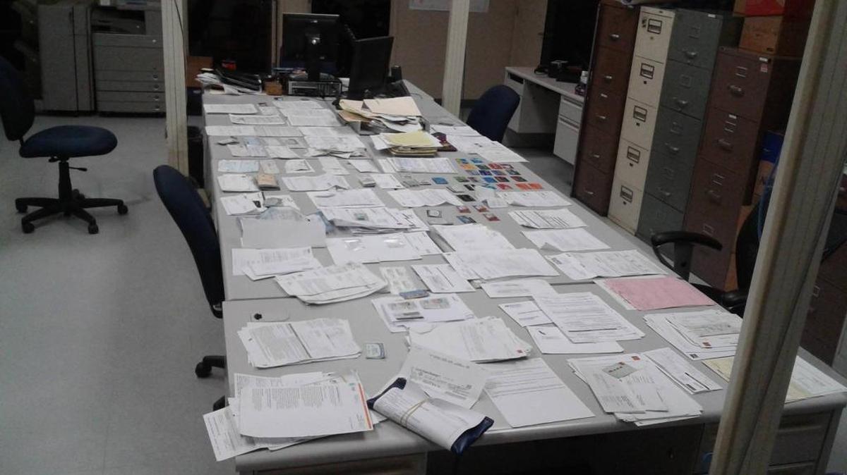 Police say each stack in the photo represents one victim. Also recovered was a large stash of credit cards.