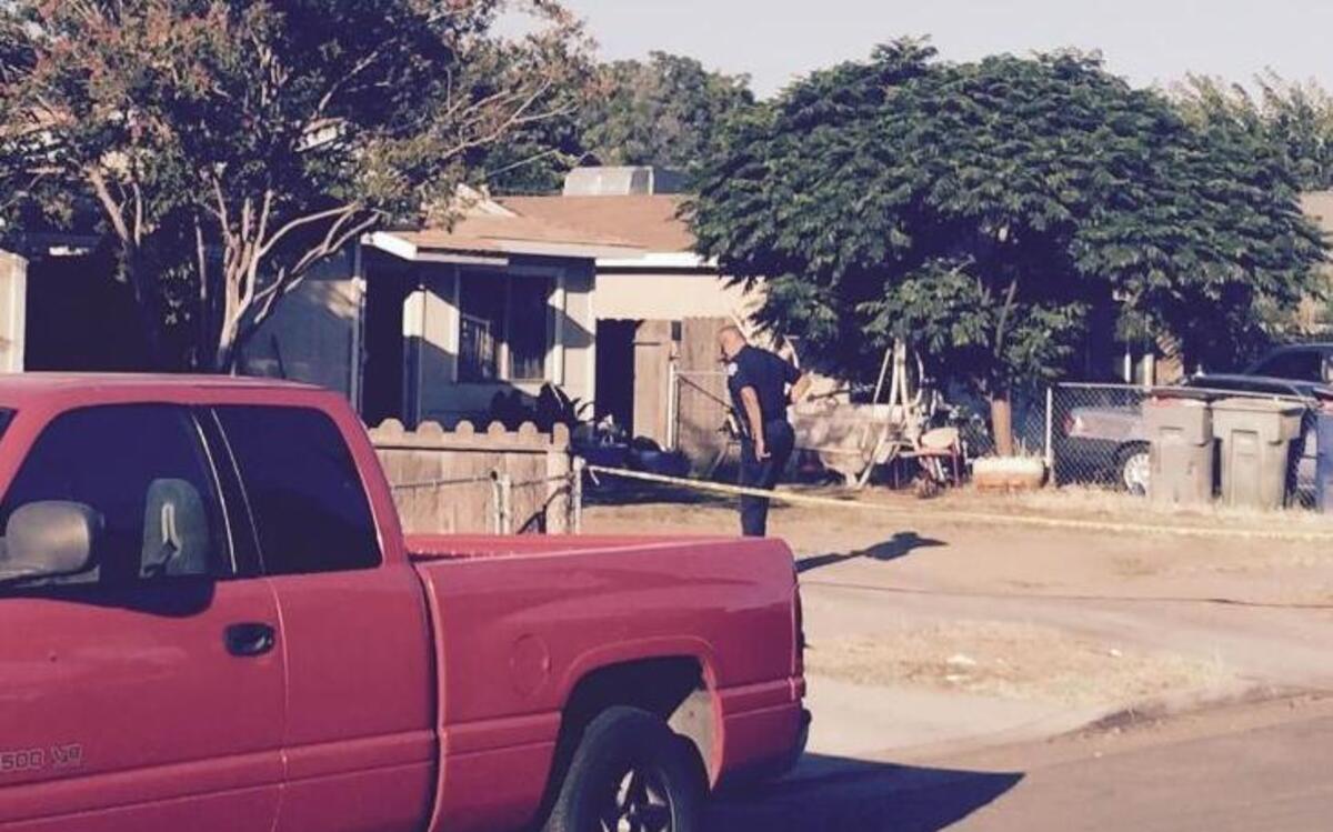 A Fresno police officer stands in front of a home on East El Monte Way where multiple rounds of gunfire broke out at the end of an all-night party in southeast Fresno. Four people were wounded.