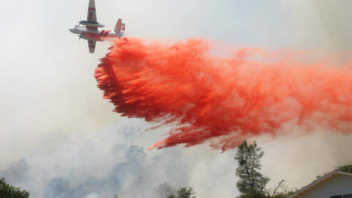 A Cal Fire plane drops retardant to help extinguish a 76-acre wild fire off North Dome Drive in Yosemite Lakes Park near Coarsegold.