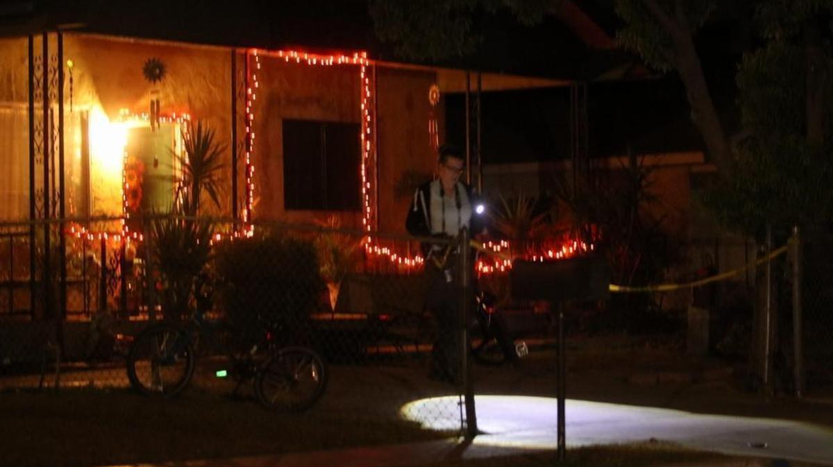 A Fresno County sheriff’s investigator surveys the scene outside the Malaga home where five people were shot Sunday night, Nov. 12.