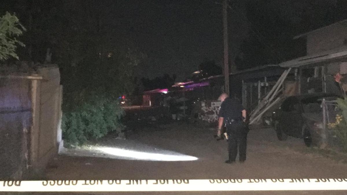 A Fresno police officer scans a darkened alley in east-central Fresno Wednesday in search of evidence after a shooting injured one person.