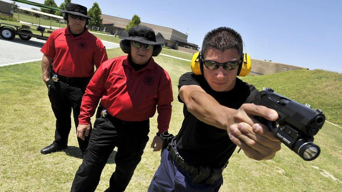 
Fresno Police Sgt. Rob Beckwith, center, reviews the shooting position of recruit Anthony Tafoya at the Regional Training Center. Officer Keith Dooms, left, looks on.

