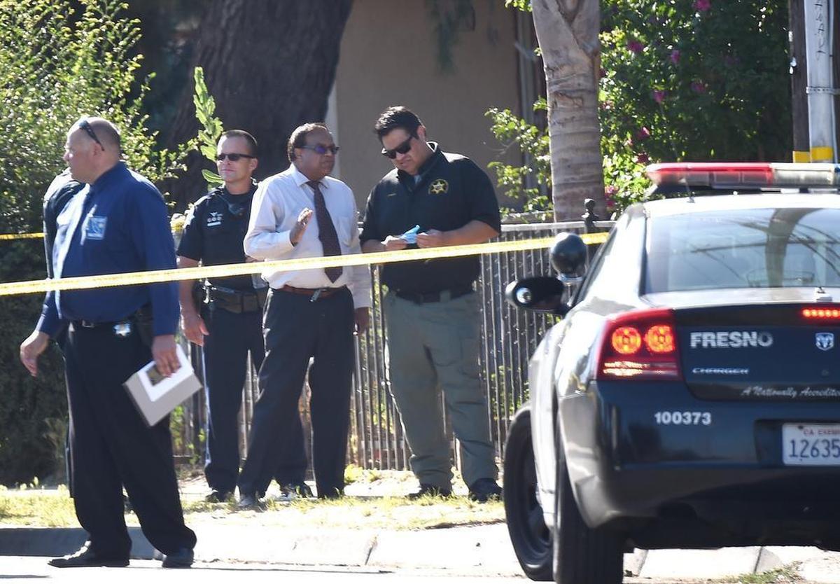 Fresno County Coroner Dr. Venu Gopal, at center in tie, confers with a county Sheriff’s Office investigator at the scene of a Fresno police officer-involved shooting Wednesday morning, June 7, 2017.