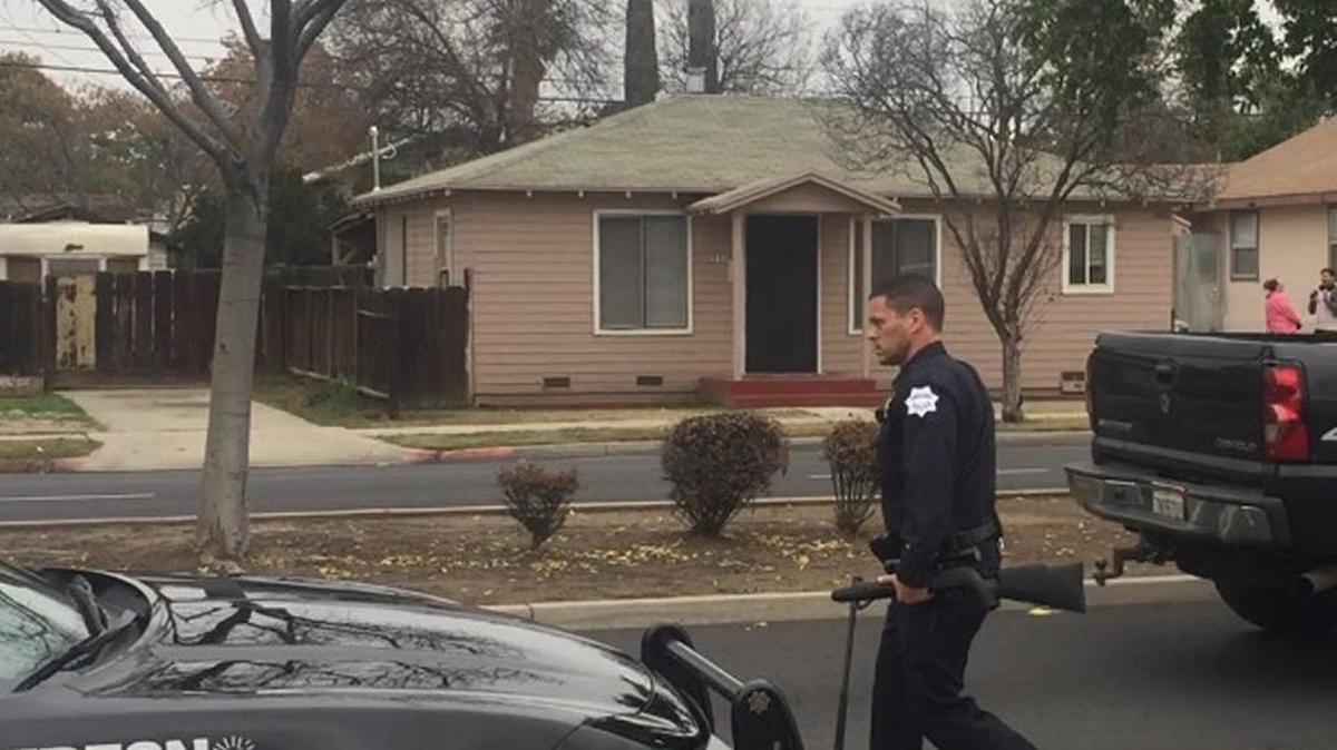 A Fresno police officer removes what turned out to be a pellet gun from a home where a man was detained after callers reported a man with a gun near Shields and Blackstone avenues.