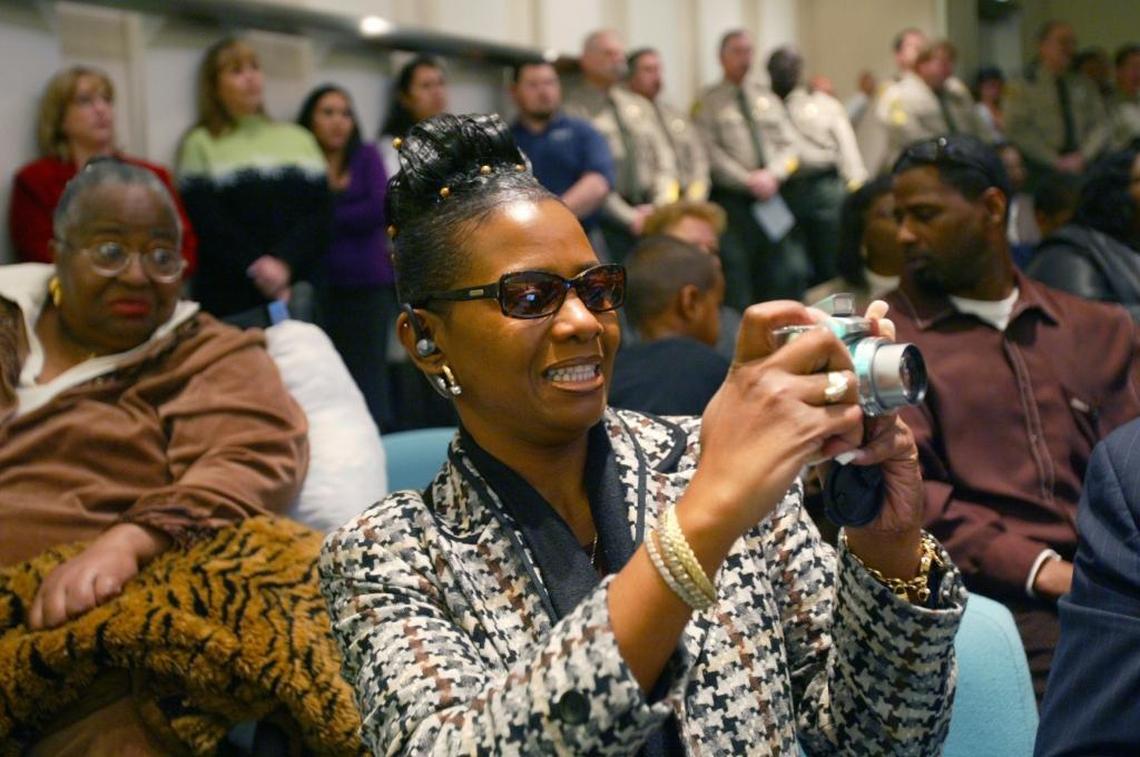 In January 2007, Kelly Foster-Nelum takes a photograph during the promotion of her brother, Keith Foster, to deputy chief of police at a packed ceremony at City Hall. Their mother, Dorothy Foster, is pictured at left.