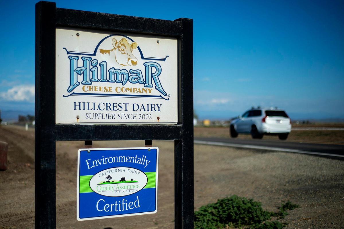 Vehicles drive past a sign identifying Hillcrest Dairy as a Hilmar Cheese Company supplier on Thursday, March 17, 2022.