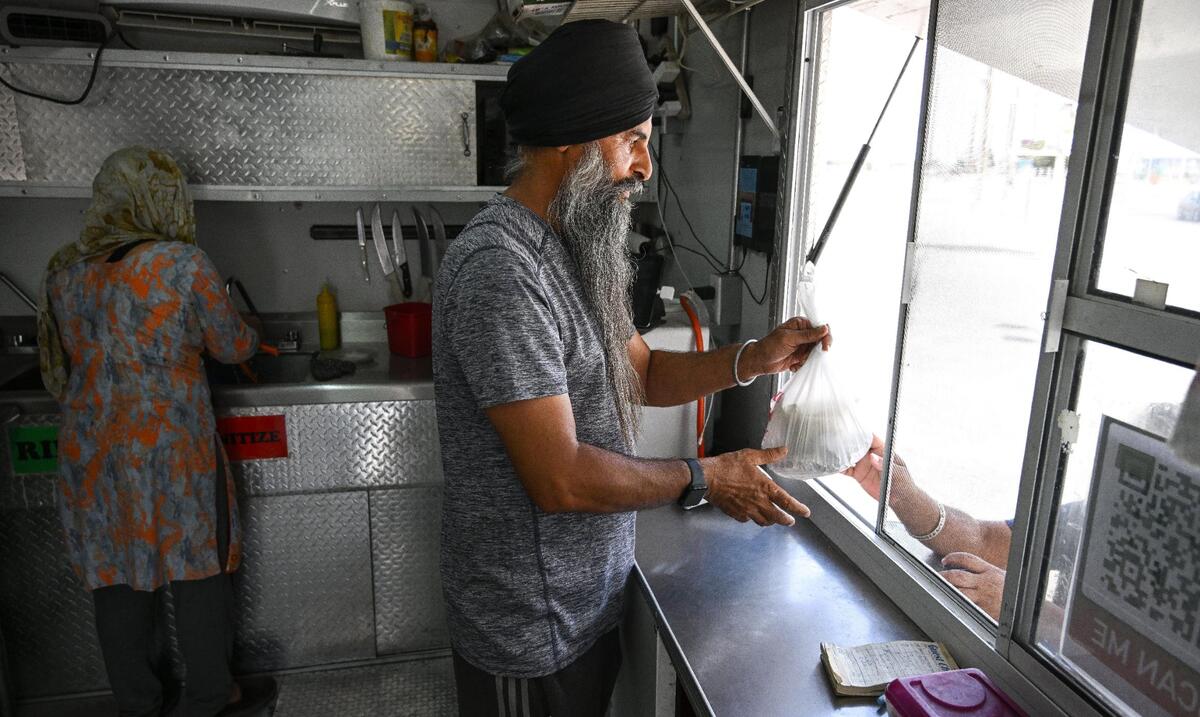 Navdeep Singh hands off an order to a customer his Punjabi Chullah & Grill food truck on Shaw Avenue near Highway 99 in Fresno on Wednesday, Aug. 16, 2023. Fresno Bee file.
