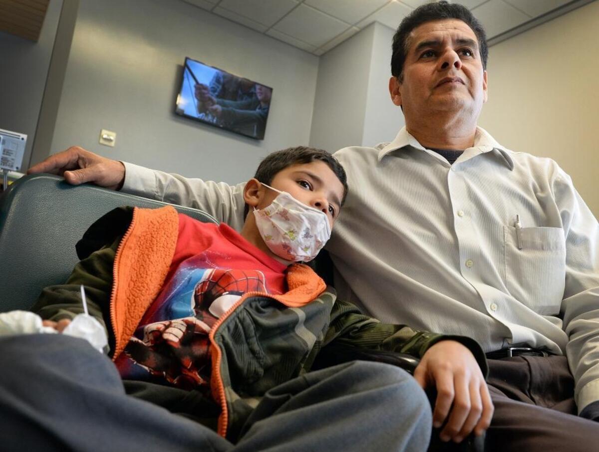Antonio Bustos, right, of Fresno, sits with his son Juan, 6, who is suffering from flu symptoms and fever while waiting to see a doctor in the waiting room of the emergency department at Community Regional Medical Center in Fresno on Monday, Jan. 22, 2018.