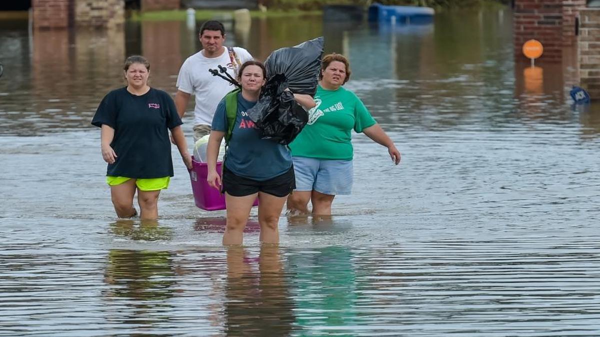 People wade in water near flood damaged homes in Highland Ridge Subdivision in Youngsville, Louisiana on Sunday. Torrential rains swamped parts of southern Louisiana, causing widespread flooding.