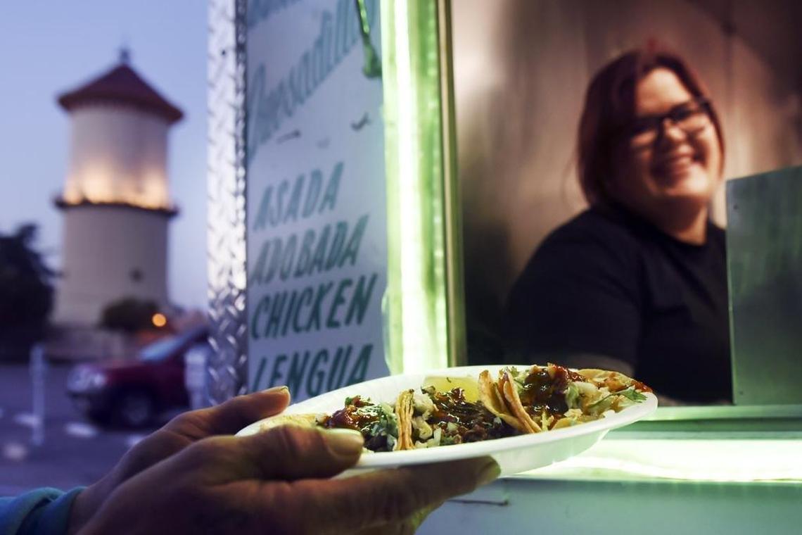 El Premio Mayor’s Bianca Loza, top, serves a plate of three tacos from the restaurant’s taco trailer in this file photo.