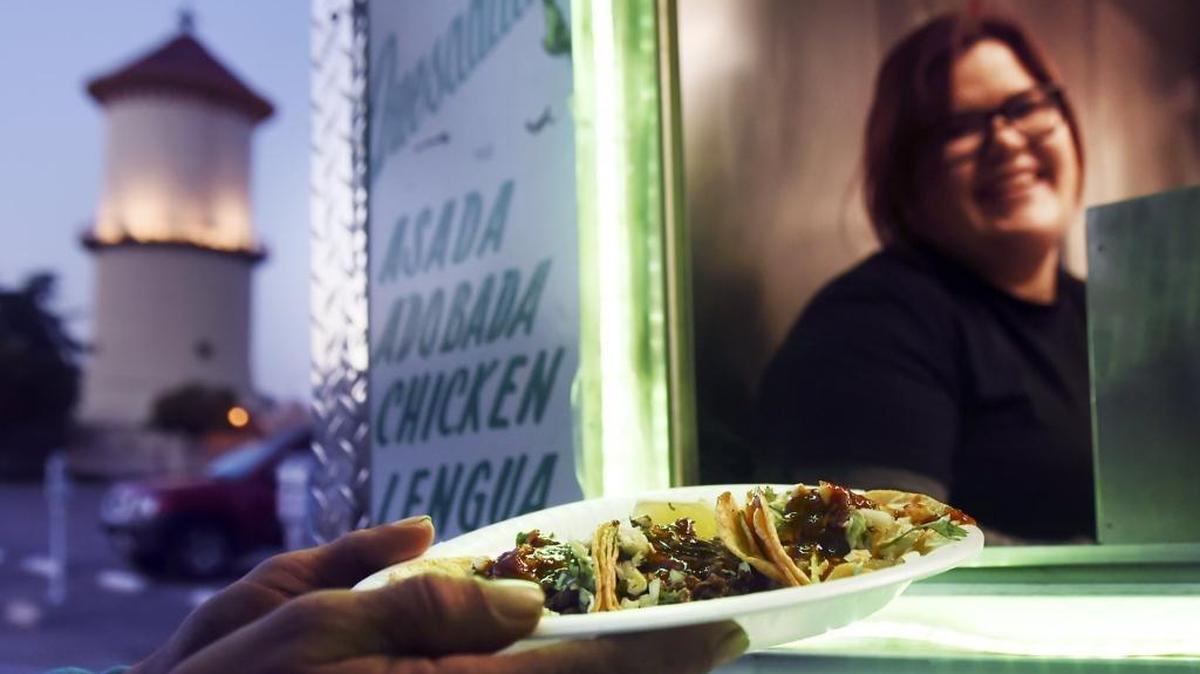 El Premio Mayor’s Bianca Loza, top, serves a plate of three tacos from the restaurant’s taco trailer in this file photo from 2016.