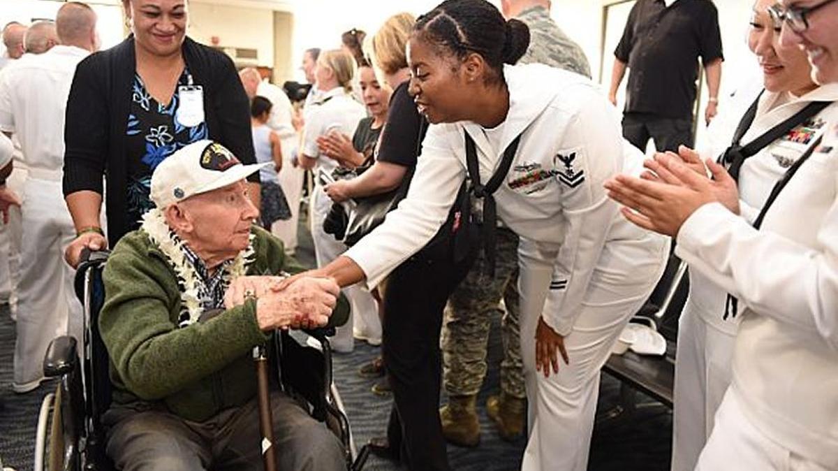 Petty Officer 2nd Class Talisha Williams of Fresno shakes the hand of a Pearl Harbor survivor arriving at Honolulu International Airport.