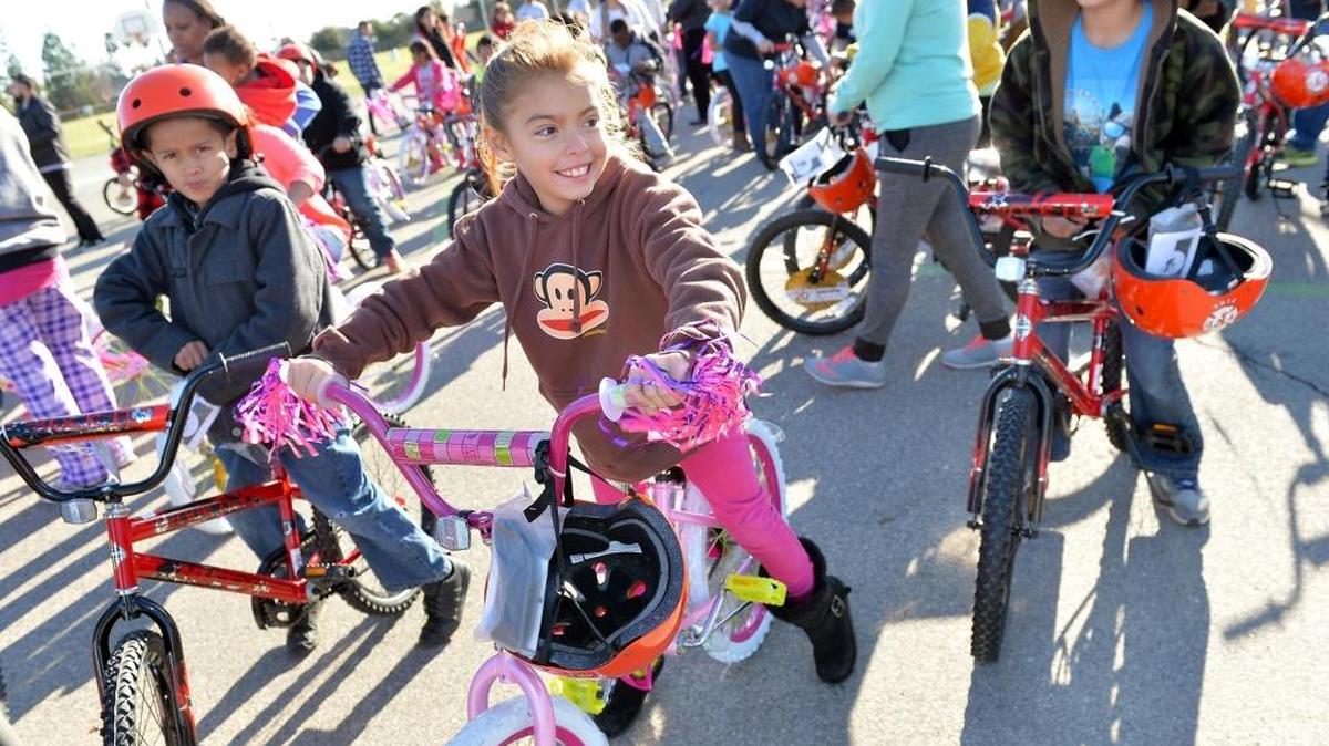 Third grader Daisy Reyna, 8, center, sits on her new bike on Monday, December 14, 2015 at Teague Elementary School in Fresno, California. Ninety-three Teague third graders received a new bike and helmet on Monday, courtesy of Celebration Church and the Fresno Fire Chief’s Foundation.