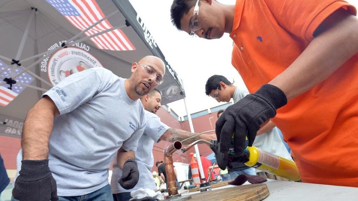 
Plumbers, Pipe and Refrigeration Fitters instructor Jonhenry Lopez, 44, left, works on a soldering project for plumbing with Antonio Lopez, 17, of Riverdale High School, at the annual Central Valley Career Tech Expo on Wednesday at the Fresno Convention Center Exhibit Hall. 
