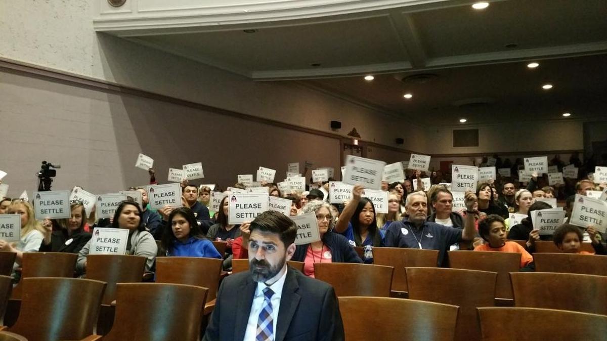 Supporters of the Fresno Teachers Association hold their “please settle” signs during Fresno Unified School District’s Board of Trustees meeting at Fresno High School on Wednesday. The FTA has been in an ongoing contract dispute with Fresno Unified.