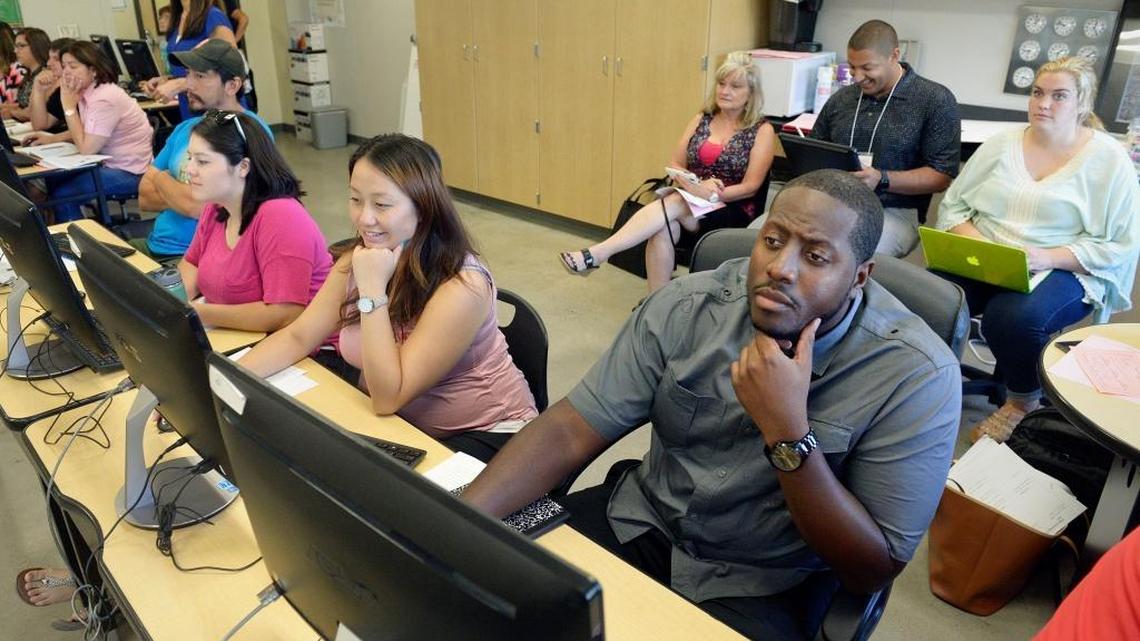 Thomas Williams, right, logs into a school computer while receiving instruction last year in a class for new teachers in Fresno Unified School District.