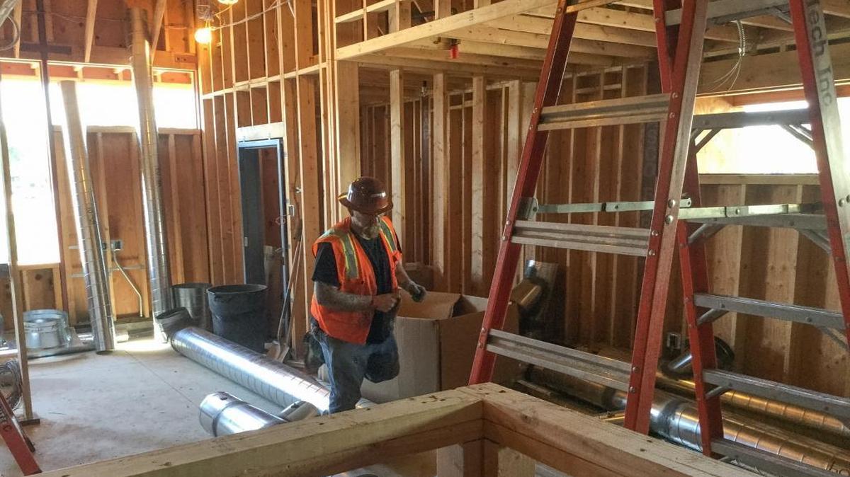 A worker for Mark Wilson Construction steps over building materials inside a new Educational Employees Credit Union branch on the Clovis West High School campus.