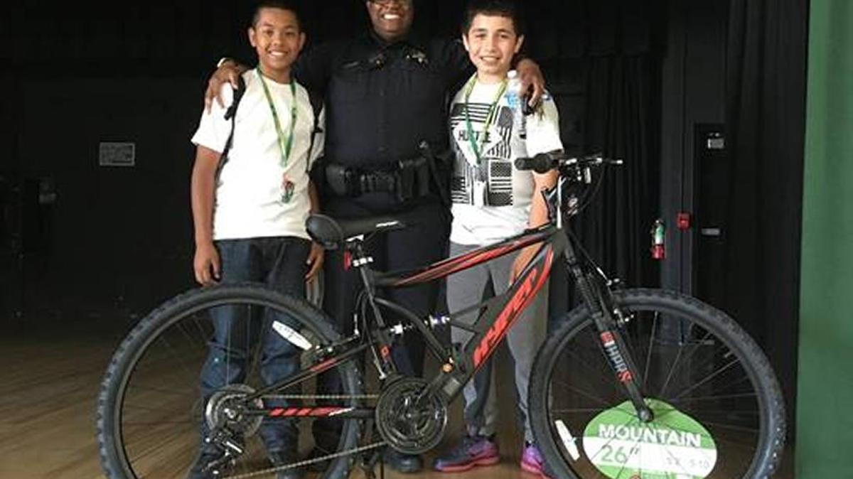 Matthew Sarim, left, with school resource officer Katrina Lloyd and Robert Gonzalez. Matthew won a new bike through a Sequoia Middle School contest, but he decided to give it to his friend, Robert, who did not have a bike.