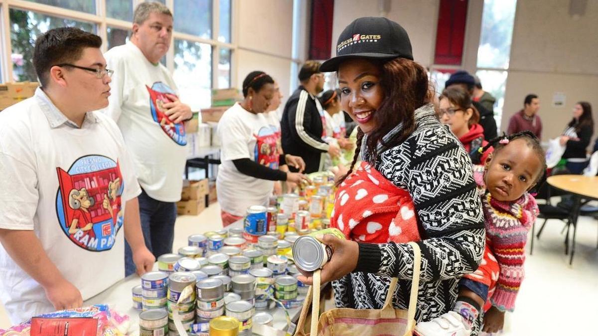 International student Faith Mensah, with her 16-month-old daughter Graciella, selects food from tables at Fresno City College’s Ram Pantry in 2017