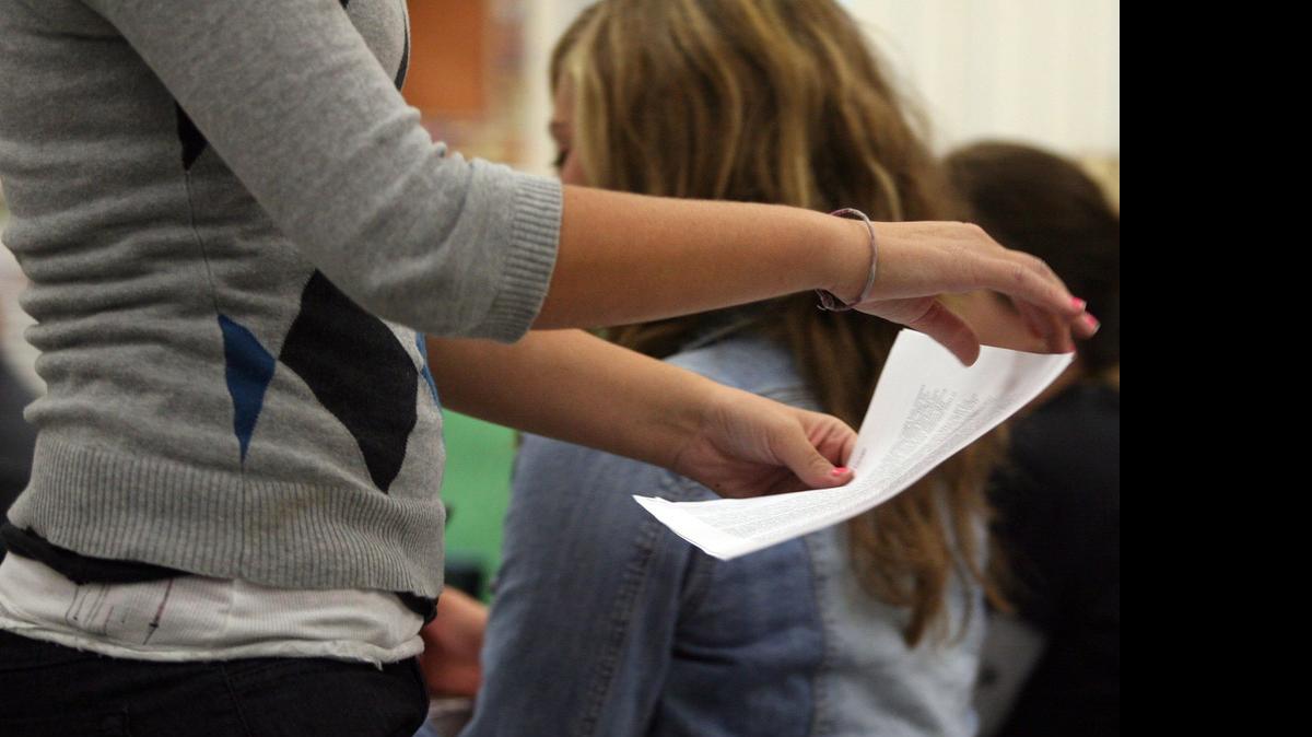 
A student at Central High School West hands in her report to the teacher.
