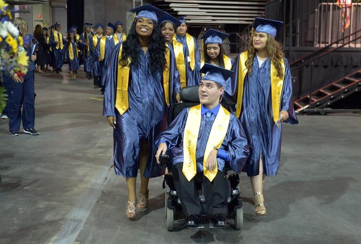 Victor Guerra, center, and his twin sister Felicia Guerra walk into the arena during commencement exercises for Sunnyside High School at the Save Mart Center in Fresno on Tuesday, June 6, 2017.