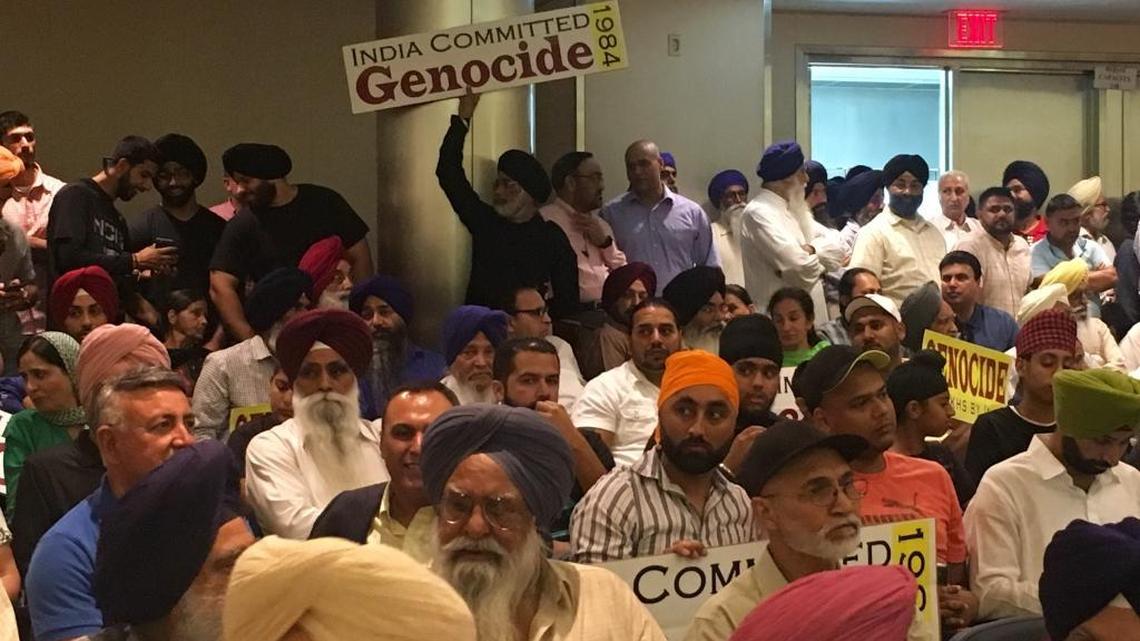 A Sikh man holds a sign that reads, “India committed genocide” before the City Council genocide resolution vote Sept. 1, 2016.