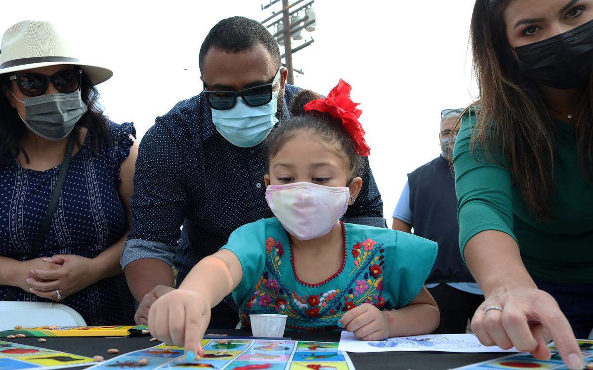 Fresno City Councilmember Nelson Esparza helps his daughter play La Lotería during the Oct. 30, 2021 Cala Gala celebration at Arte Américas.