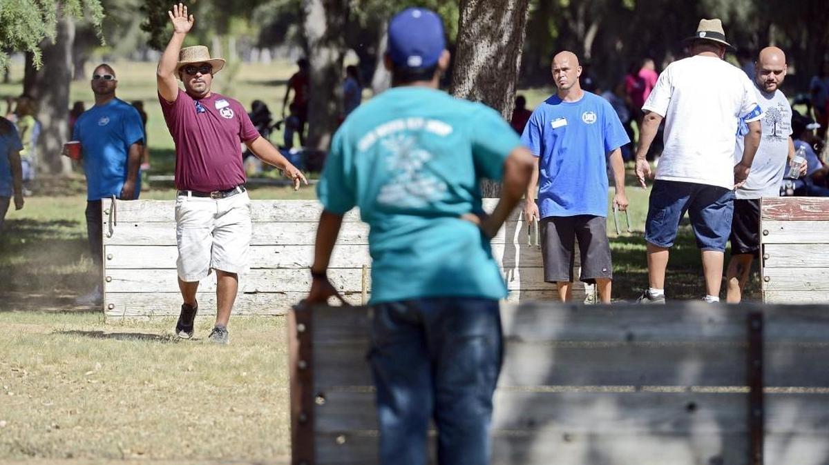 
Rick Flores, above left, of Fresno throws a horseshoe while competing with family members in the annual horseshoe competition during the Flores family reunion at Kearney Park west of Fresno Sunday. About 300 members of the family got together at the park for their 32nd annual Labor Day family reunion. The original event started with 13 brothers and sisters of the Flores family in San Joaquin. The event has since expanded considerably to where it is today. Flores is the son of one of the original 13 family members. 
