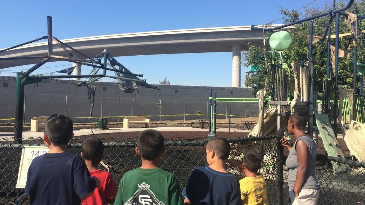 
Neighborhood children assess the damage after the Romain Playground structure burned Sunday afternoon, melting the plastic slides and sending a black plume of smoke into the air. 

