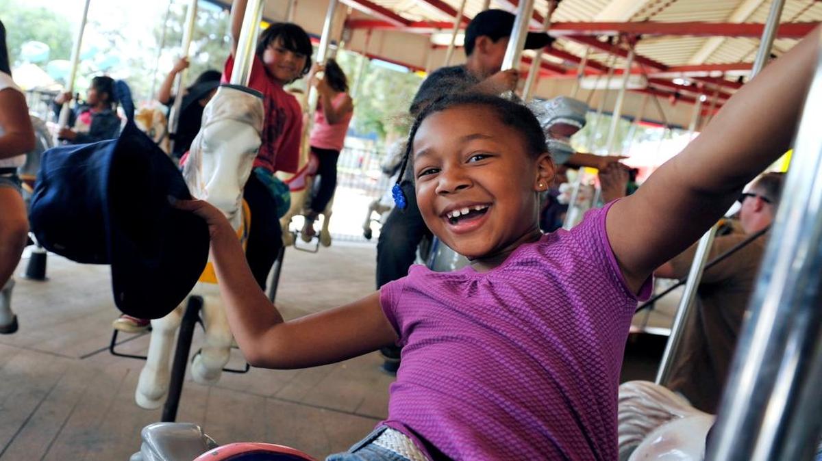 Jordan Shynett, 7, waves her hat as she rides the carousel at Playland. in 2014