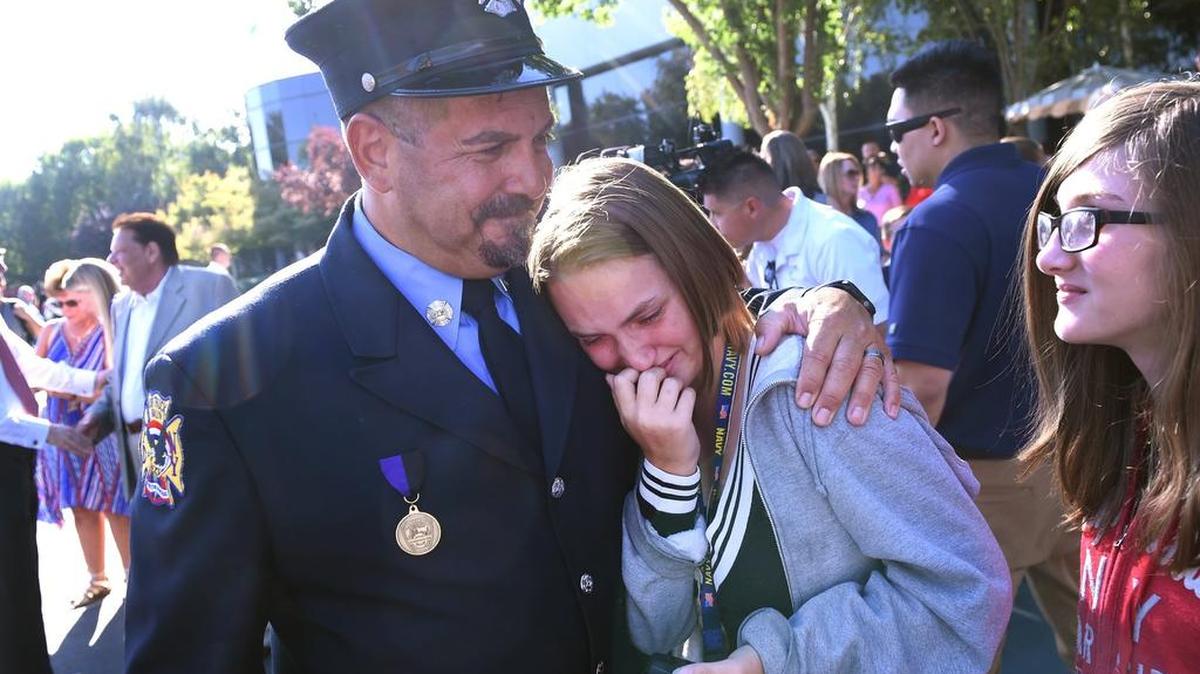 Former New York City firefighter Andy Isolano, left, consoles Lillian Harguess, 16, center, following the 9/11 public observance at the California Memorial, Tuesday morning, Sept. 11, 2018 in Clovis. Harguess, who was not born at the time of the terrorist attacks, said the event made her think about those who grew up without a father-figure, and inspires her to protect the loved ones in her life.