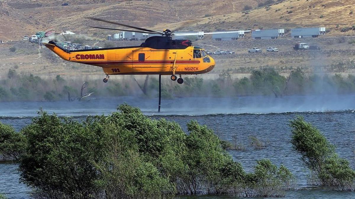 A firefighting helicopter gets water out of Isabella Lake near Wofford Heights before making another water drop on the Cedar Fire. The fire base camp is seen across the lake (in the background) in the Camp 9 area. As of Tuesday, the fire had burned 21,000 and was 5 percent contained.