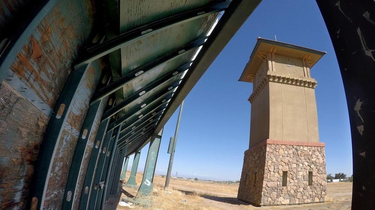 
The clock tower seen through girders of an outfield wall, with paint peeling on the plywood, at one of the shuttered Granite Park baseball fields in central Fresno.
