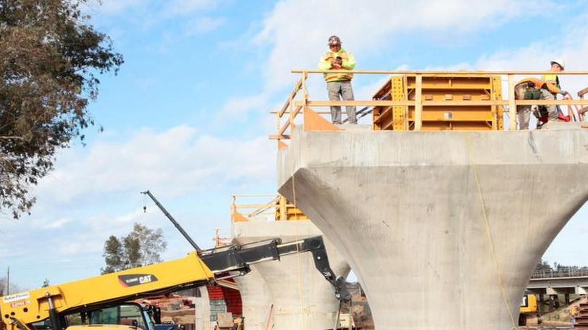 Construction crews work on steel-reinforced concrete supports for a high-speed-rail bridge over the Fresno River and Highway 145 east of Madera.