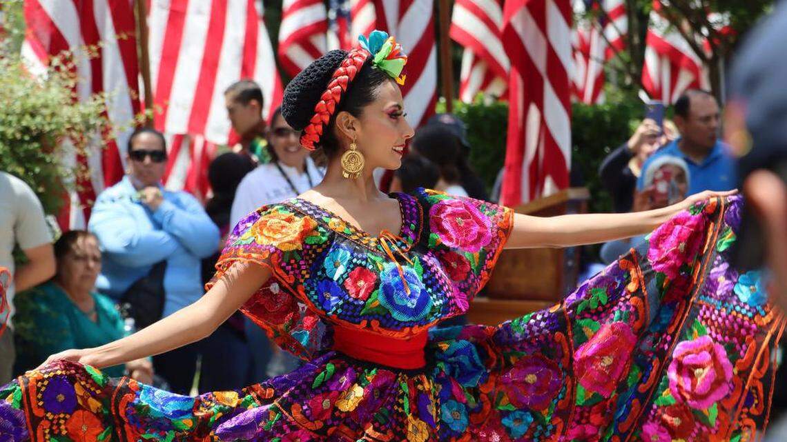 Una integrante del Ballet Folklórico Guadalajara actúa frente a las banderas de Estados Unidos durante la ceremonia del Memorial Day en el Courthouse Park en Madera, el 29 de mayo de 2023.